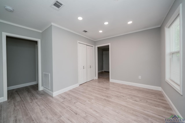 unfurnished bedroom featuring light wood-type flooring, ornamental molding, and a closet