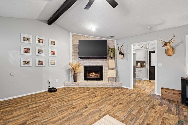 unfurnished living room featuring vaulted ceiling with beams, a textured ceiling, and light wood-style flooring