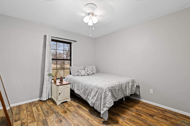 bedroom with dark wood-style floors, a textured ceiling, and baseboards