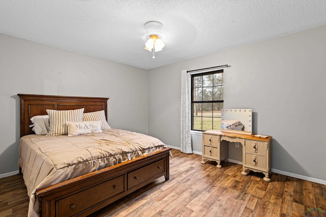 bedroom with baseboards, a textured ceiling, and light wood finished floors