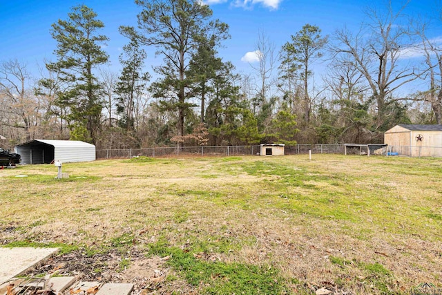 view of yard with an outbuilding, a carport, and fence