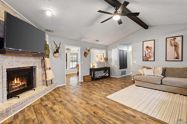 living room featuring visible vents, lofted ceiling with beams, a textured ceiling, and wood finished floors