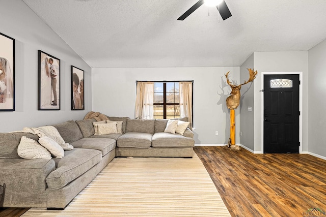 living room with ceiling fan, a textured ceiling, wood finished floors, baseboards, and vaulted ceiling