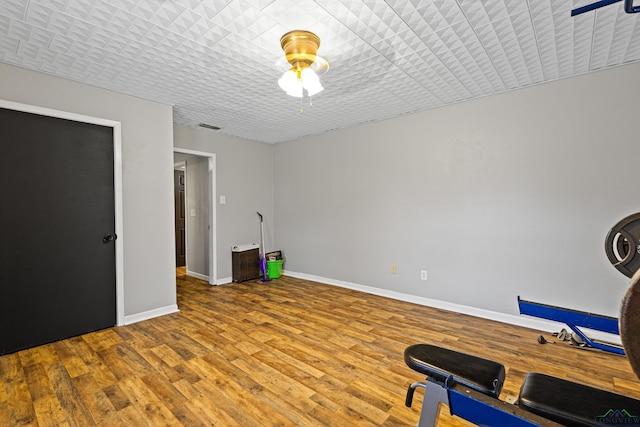 workout room with wood finished floors, visible vents, and baseboards