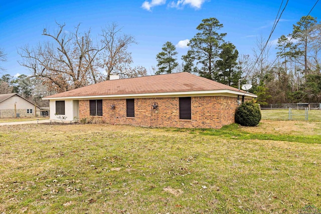 back of house with brick siding, a yard, and fence