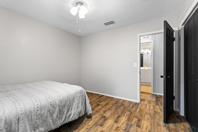 bedroom with baseboards, a textured ceiling, visible vents, and dark wood-style flooring