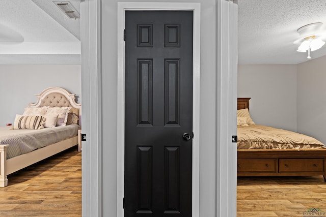 bedroom with light wood-type flooring, visible vents, and a textured ceiling