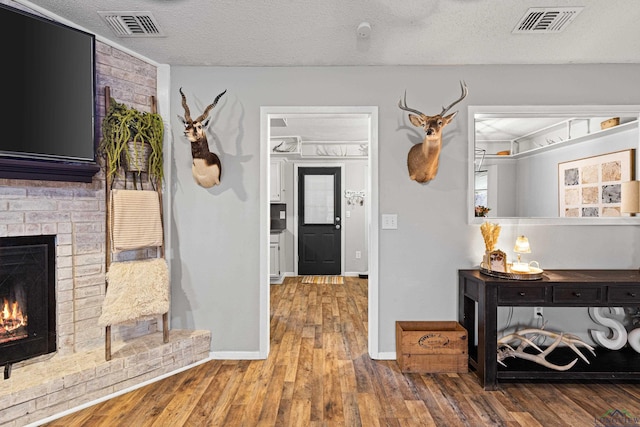 interior space featuring visible vents, a textured ceiling, and wood finished floors