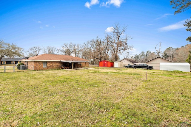 view of yard with a detached garage, fence, a shed, driveway, and an outdoor structure