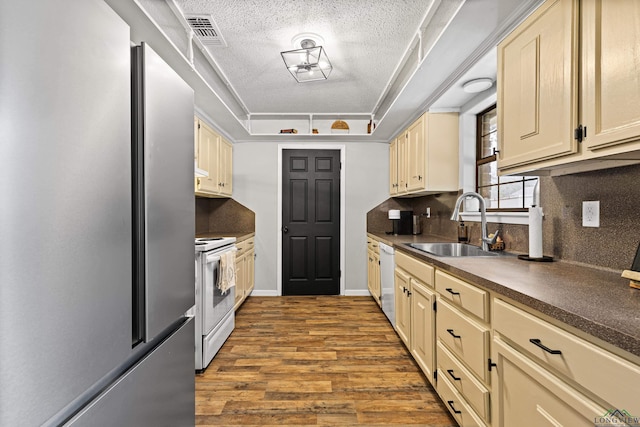 kitchen featuring a raised ceiling, visible vents, a sink, light wood-type flooring, and white appliances