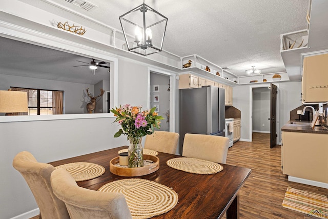 dining space featuring baseboards, visible vents, dark wood-style flooring, and a textured ceiling