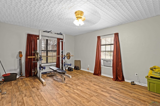 exercise area with light wood-style floors, cooling unit, and baseboards