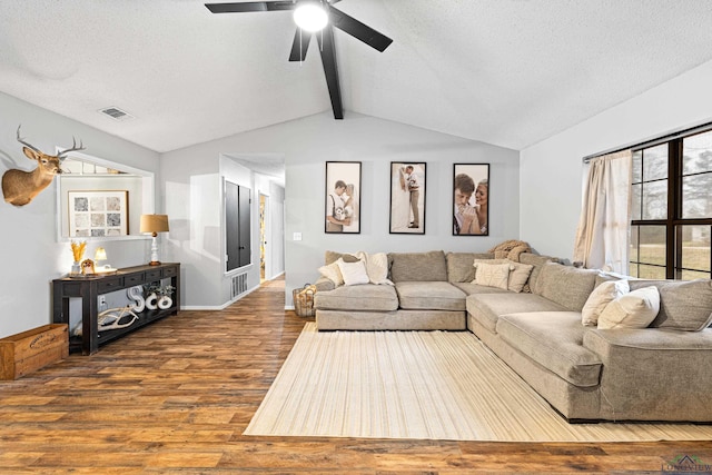 living area with lofted ceiling with beams, a textured ceiling, visible vents, and wood finished floors