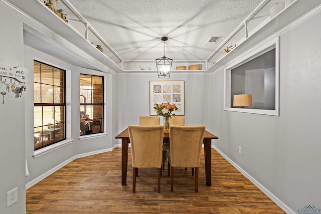 dining room featuring a textured ceiling, wood finished floors, visible vents, and baseboards