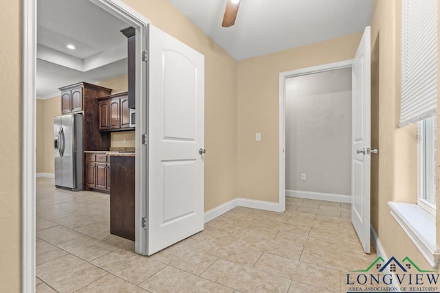 hall featuring light tile patterned floors and baseboards