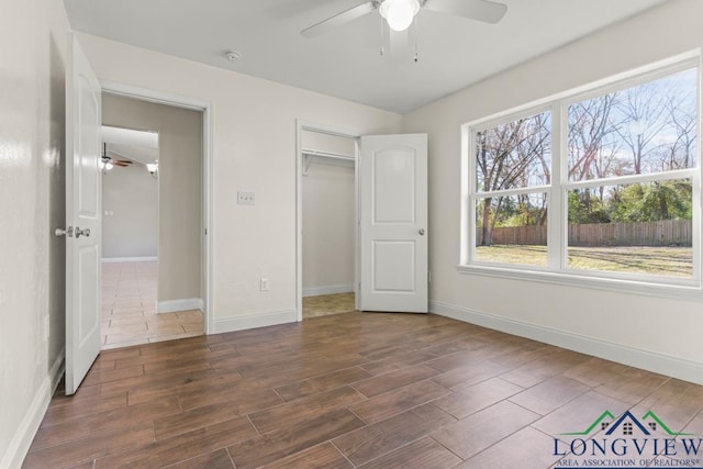 unfurnished bedroom featuring a closet, baseboards, wood finished floors, and a ceiling fan