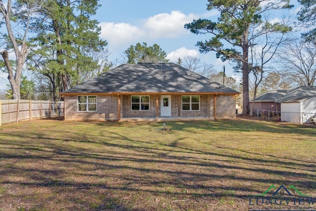 back of property featuring brick siding, a yard, and fence