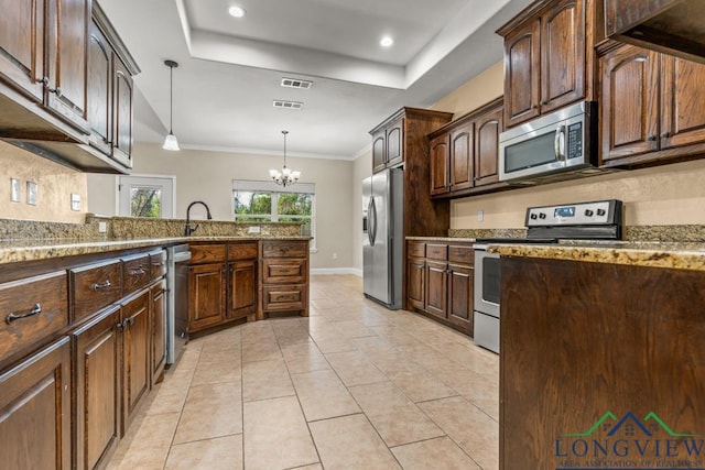 kitchen with light tile patterned flooring, appliances with stainless steel finishes, a tray ceiling, and light stone countertops