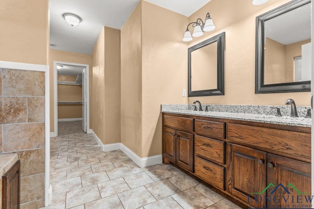 bathroom featuring double vanity, baseboards, tile patterned flooring, and a sink