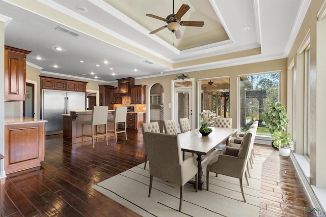 dining space featuring a tray ceiling, dark hardwood / wood-style floors, ornamental molding, and ceiling fan