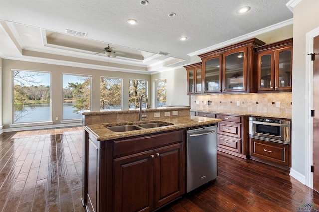 kitchen featuring ornamental molding, stainless steel appliances, a raised ceiling, sink, and a water view