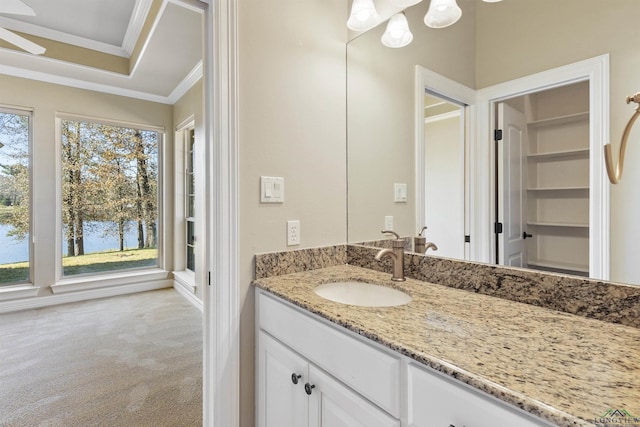 bathroom featuring a tray ceiling, crown molding, vanity, and ceiling fan