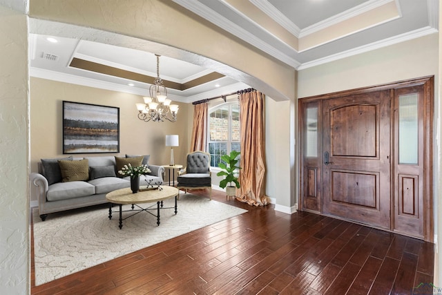 entrance foyer with dark hardwood / wood-style flooring, a raised ceiling, crown molding, and an inviting chandelier