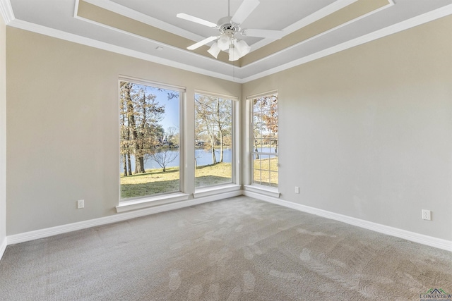 spare room featuring a wealth of natural light, ceiling fan, a raised ceiling, a water view, and ornamental molding