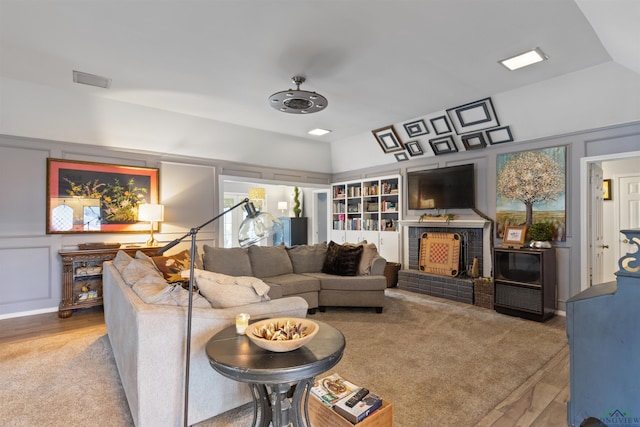 living room with ceiling fan, lofted ceiling, a brick fireplace, and light wood-type flooring