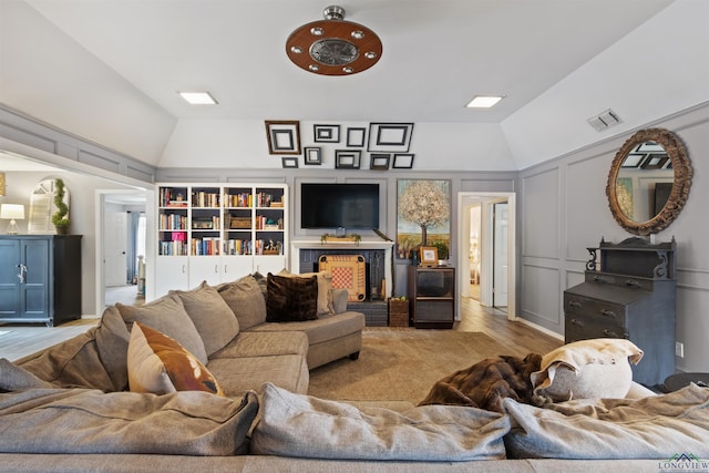 living room with lofted ceiling, a brick fireplace, and light hardwood / wood-style flooring