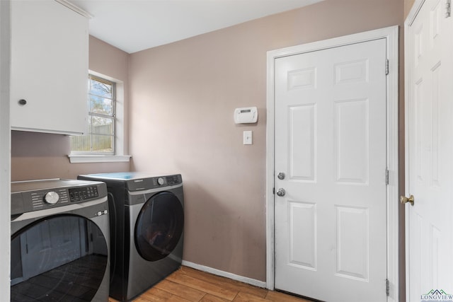 laundry room with cabinets, washer and clothes dryer, and light hardwood / wood-style flooring