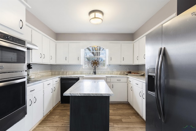 kitchen featuring sink, a center island, appliances with stainless steel finishes, white cabinets, and backsplash