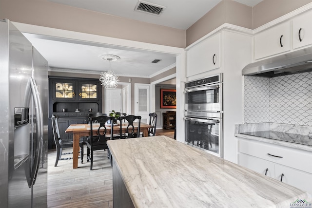 kitchen featuring pendant lighting, white cabinetry, tasteful backsplash, and stainless steel appliances