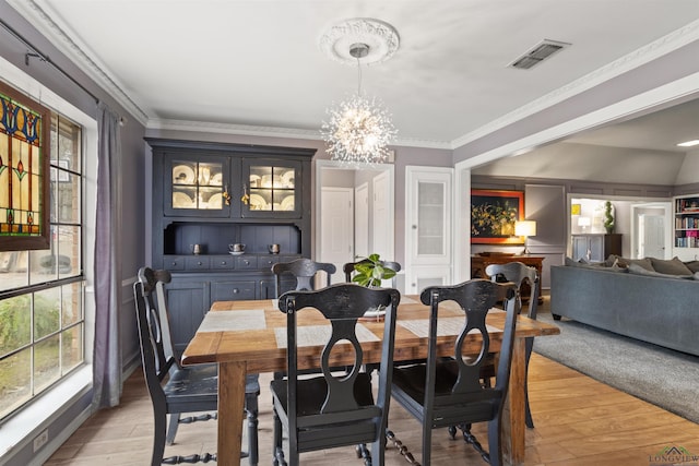 dining area featuring ornamental molding, a notable chandelier, and light hardwood / wood-style flooring