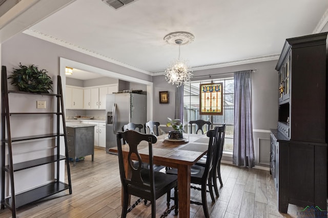 dining area featuring an inviting chandelier, crown molding, and light hardwood / wood-style floors