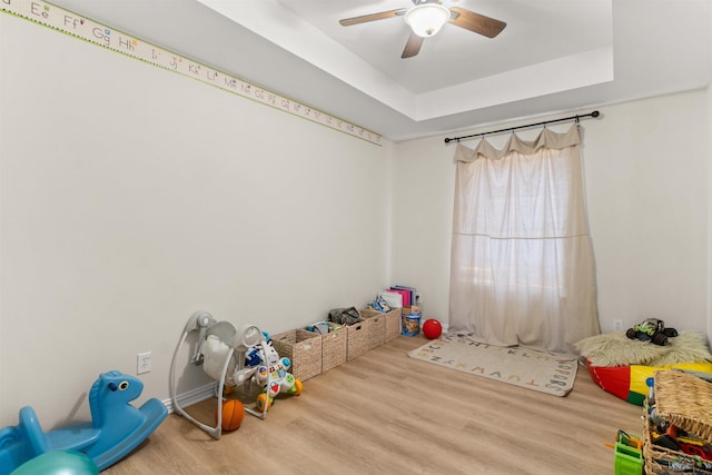 rec room featuring hardwood / wood-style floors, ceiling fan, and a tray ceiling