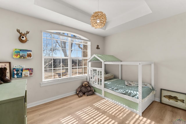 bedroom with hardwood / wood-style flooring and a tray ceiling