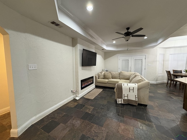 living room featuring ceiling fan, a raised ceiling, and ornamental molding