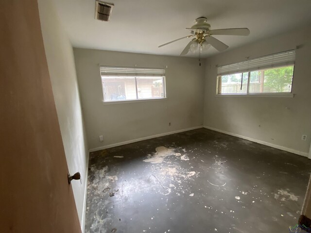 empty room with baseboards, a ceiling fan, and visible vents