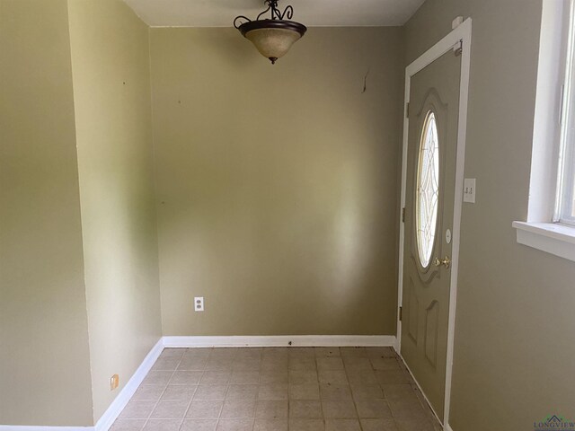entryway with baseboards and light tile patterned flooring