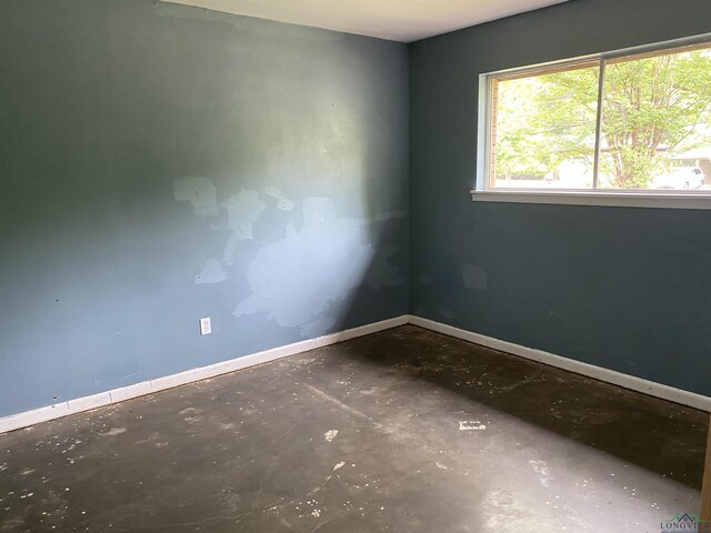 spare room featuring concrete floors and baseboards