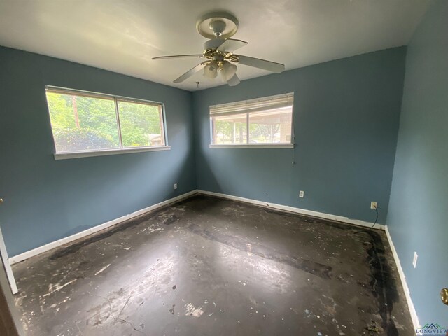 spare room with a ceiling fan and baseboards