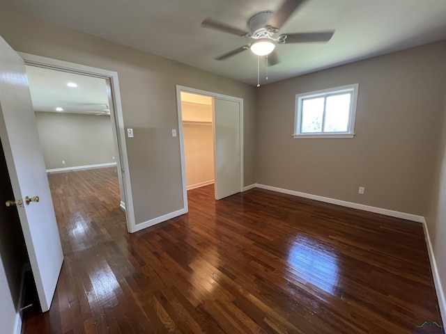 unfurnished bedroom featuring dark hardwood / wood-style flooring, a closet, a spacious closet, and ceiling fan