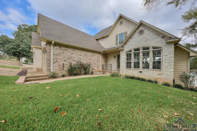 view of front of property with stone siding, brick siding, a front lawn, and roof with shingles