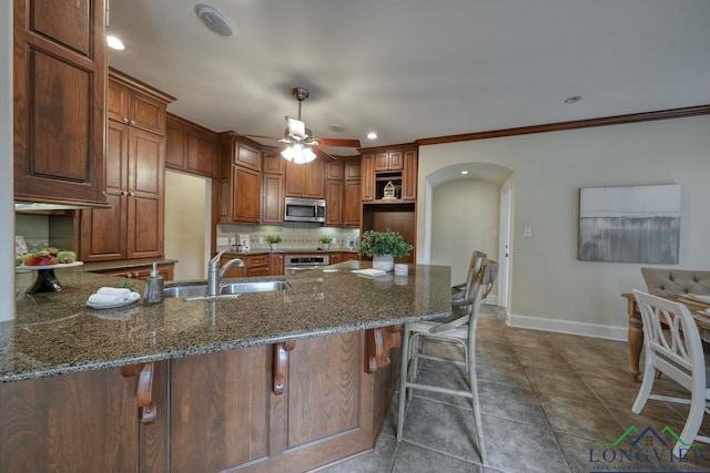 521 Hideaway Ln, Central, Hideaway, TX 75771 - kitchen with arched walkways, a peninsula, baseboards, appliances with stainless steel finishes, and dark stone counters