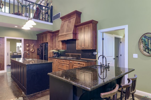 kitchen featuring fridge with ice dispenser, a kitchen island with sink, sink, and decorative backsplash