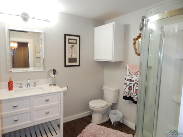 bathroom featuring toilet, vanity, a shower with shower door, and wood-type flooring