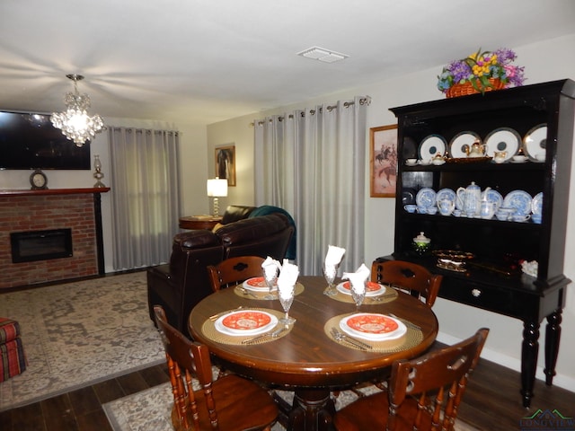 dining room featuring a chandelier, dark hardwood / wood-style flooring, and a brick fireplace