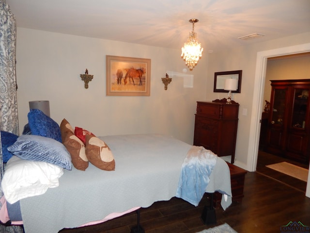 bedroom featuring dark hardwood / wood-style floors and a notable chandelier