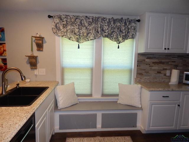 interior space featuring white cabinetry, sink, dishwasher, light stone counters, and backsplash